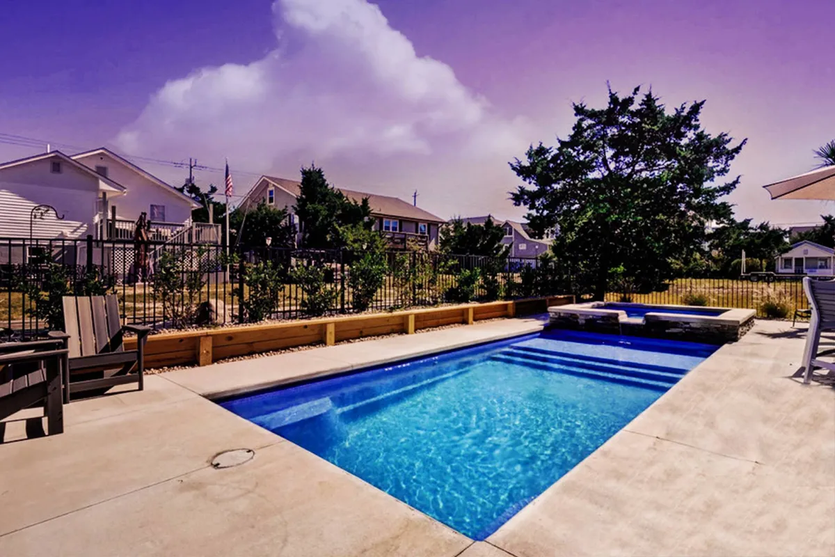 A relaxing exterior shot of a resort-style swimming pool surrounded by lush landscaping and outdoor seating. The setting invites families to unwind together after a day of exploration or boardwalk fun, tying into the idea of comfort and shared amenities.