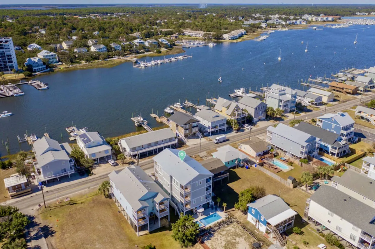 This wide view captures the waterfront setting with a marina, residential homes, and swimming pools visible. The tranquil water and community vibe reflect opportunities for boating, social gatherings, and enjoying the scenic location.