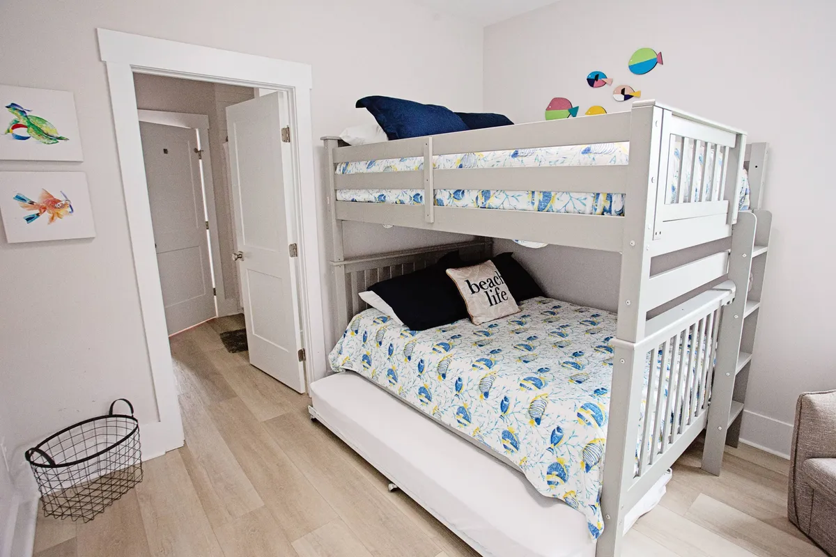 A lively bunk room with a colorful bunk bed, playful bedding, and decorative fish wall art, creating a fun, beachy atmosphere perfect for kids. The room feels energetic and designed for imaginative play and restful nights.